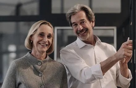 Casal de pessoas sorrindo, uma ao lado da outra